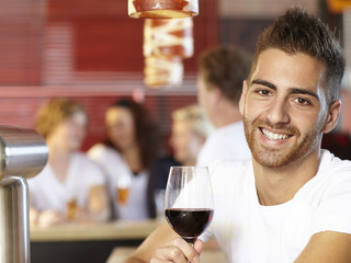 Young man in a bar drinking a glass of wine