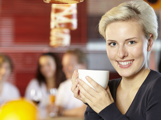 Pretty blonde woman with a cup of coffee sitting in a bar