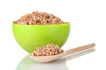 Boiled buckwheat in a green bowl isolated on white