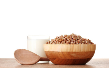Boiled buckwheat in a wooden bowl with a glass of milk