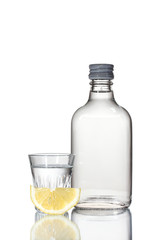 Bottle of vodka and wineglass with lemon isolated on white