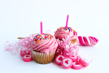 Two pink cupcakes with candy and ribbon  on white background