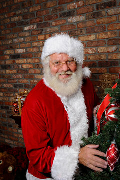 Santa Claus Smiling next to a Christmas Tree