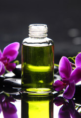 Reflection of bottle of essential oil and pink orchid