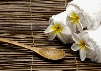 Roller Spa towels with frangipani flower and spoon on mat