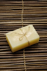 Bar of natural handmade soap on wooden mat.