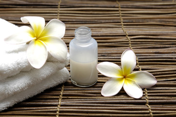 Obraz na płótnie Canvas Massage oil and frangipani flower on white towel