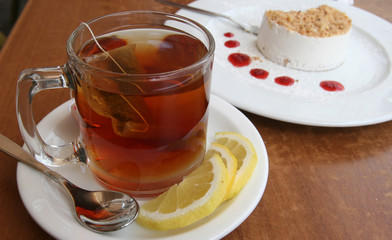 A cup of tea with lemon and a cake