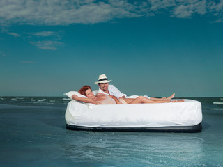 young couple laying bed floating on sea