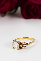 Golden diamond ring and rose on white background