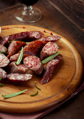 Cured dry sausage with rosemary on wooden board