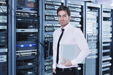 businessman with laptop in network server room