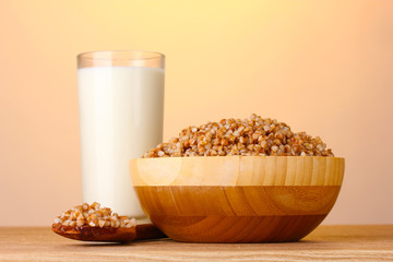 Boiled buckwheat in a wooden bowl with a glass of milk