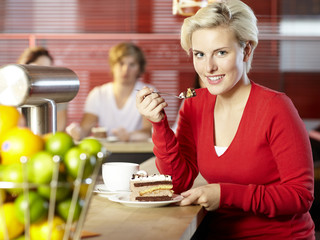 Blonde woman in a bar relishes a piece of cake
