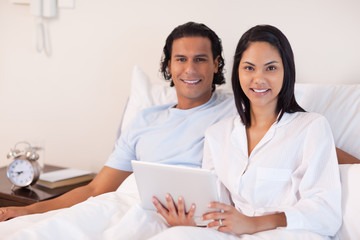 Couple sitting on the bed with their tablet pc