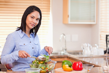 Obraz na płótnie Canvas Woman stirring her salad in the kitchen