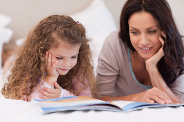 Little girl reading bedtime story with her mother