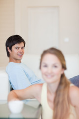 Portrait of a woman having a tea while her fiance is sitting on