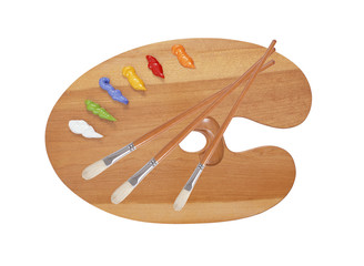 wooden art palette with blobs of paint and a brush on white back