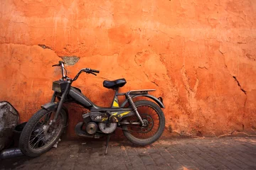 Gordijnen Old moped leans against an orange wall © Pete Niesen Photo