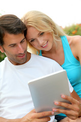 Couple laying on deck chair with electronic tablet