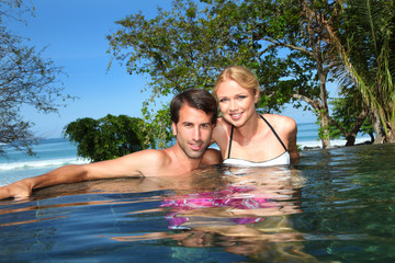 Cheerful couple swimming in resort pool