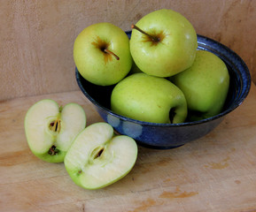 Blue Bowl of Green Apples with halved apple