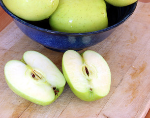 Two halves of an apple next to a blue bowl