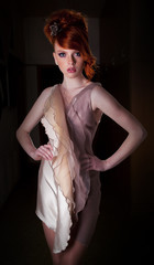 Stylish redheaded young woman standing in fashion dress