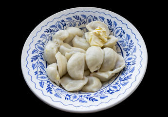 The blue patterned plate full of dumplings, seasoned with a piec