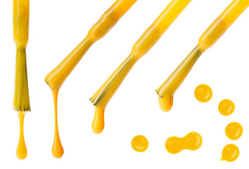 Set of yellow nail polish brushes and drops isolated on white