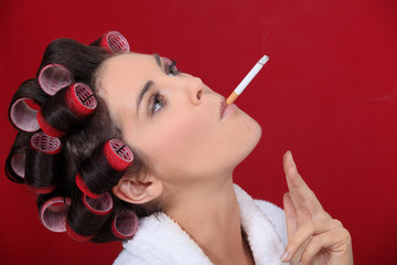 Obraz premium Smoking woman with her hair in rollers