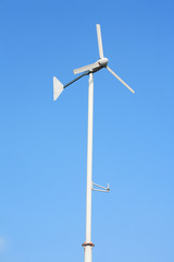 white wind turbine on clear blue sky.