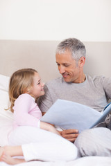 Obraz premium Portrait of a smiling father reading a story to his daughter