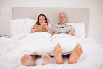 Fototapeta premium Man reading the news while his wife is reading a book