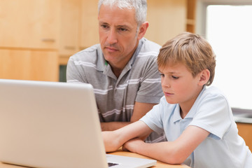Fototapeta premium Boy and his father using a laptop