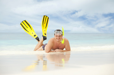 Happy man with snorkeling equipment on the beach
