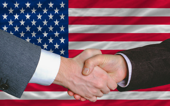 businessmen handshake after good deal in front of america flag