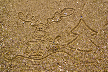 Reindeer, gift and christmas tree drawn on sand