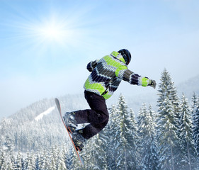 Snowboarder at jump inhigh mountains at sunny day