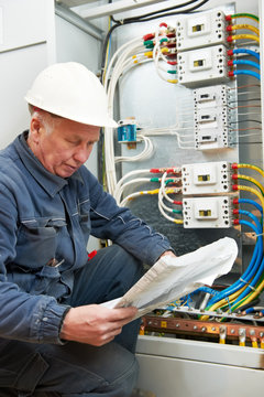 Electrician at wiring with working drawings
