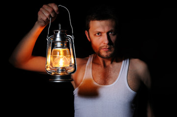 Man with a kerosene lamp on black background