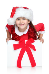 Happy little girl in Santa hat looks out of gift box