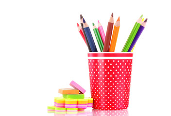 red glass with colorful pencils and stationery isolated on white