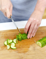 Woman's hands cutting cucumber