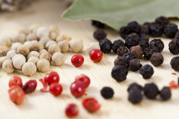 white ,black and red peppercorns close up on wooden surface
