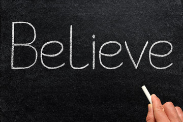 Believe, written with chalk on a blackboard.