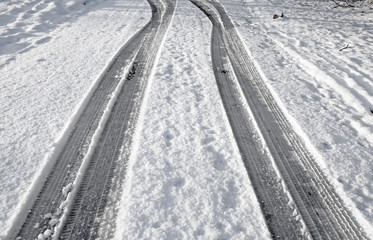 Close up tyre tracks in snow on a road.