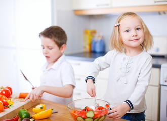 Two little kids making salad