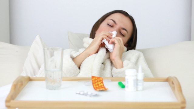 Sick woman blowing nose and putting thermometer in mouth